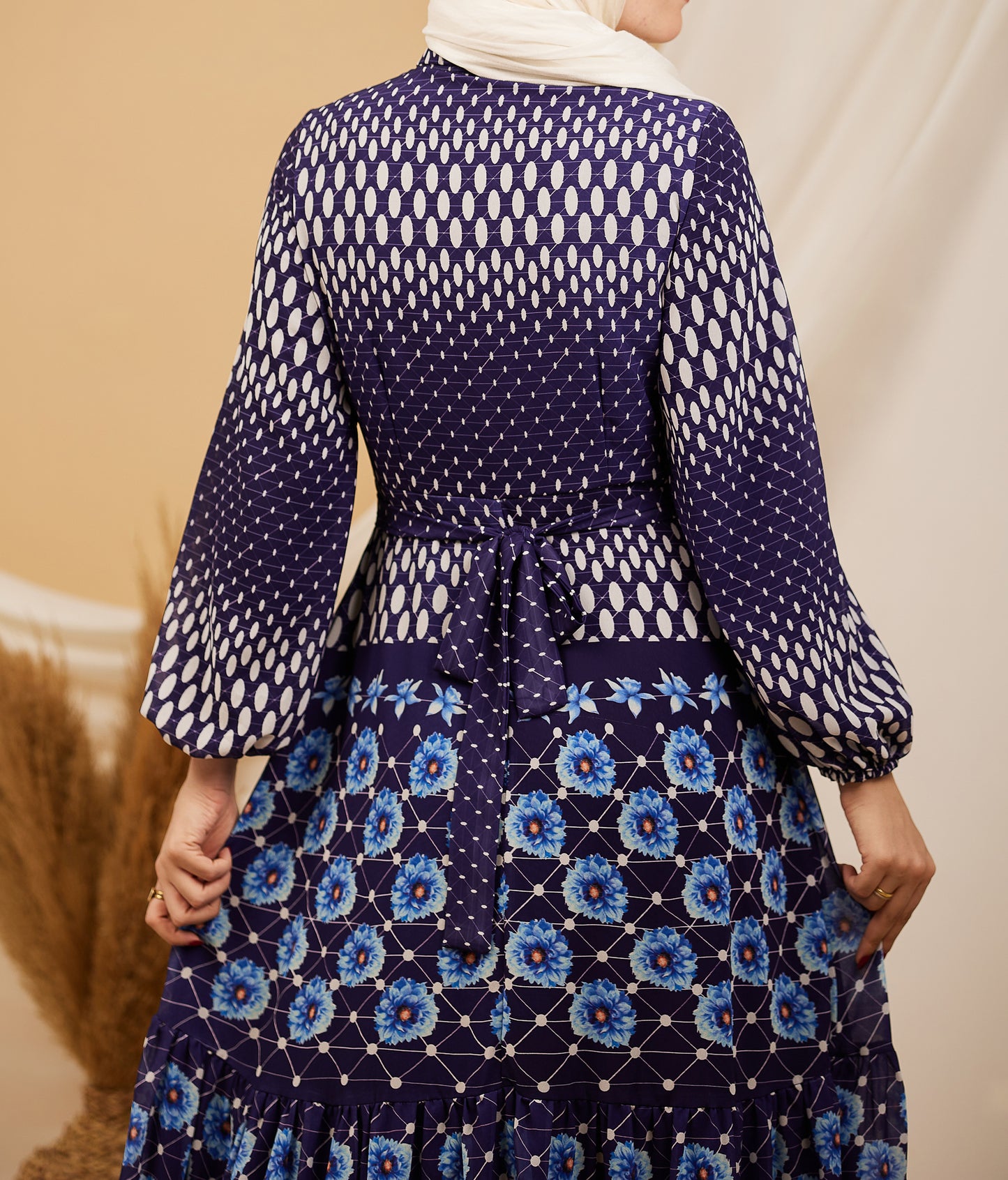 Back view of a navy floral chiffon maxi dress featuring a tie-back and floral design