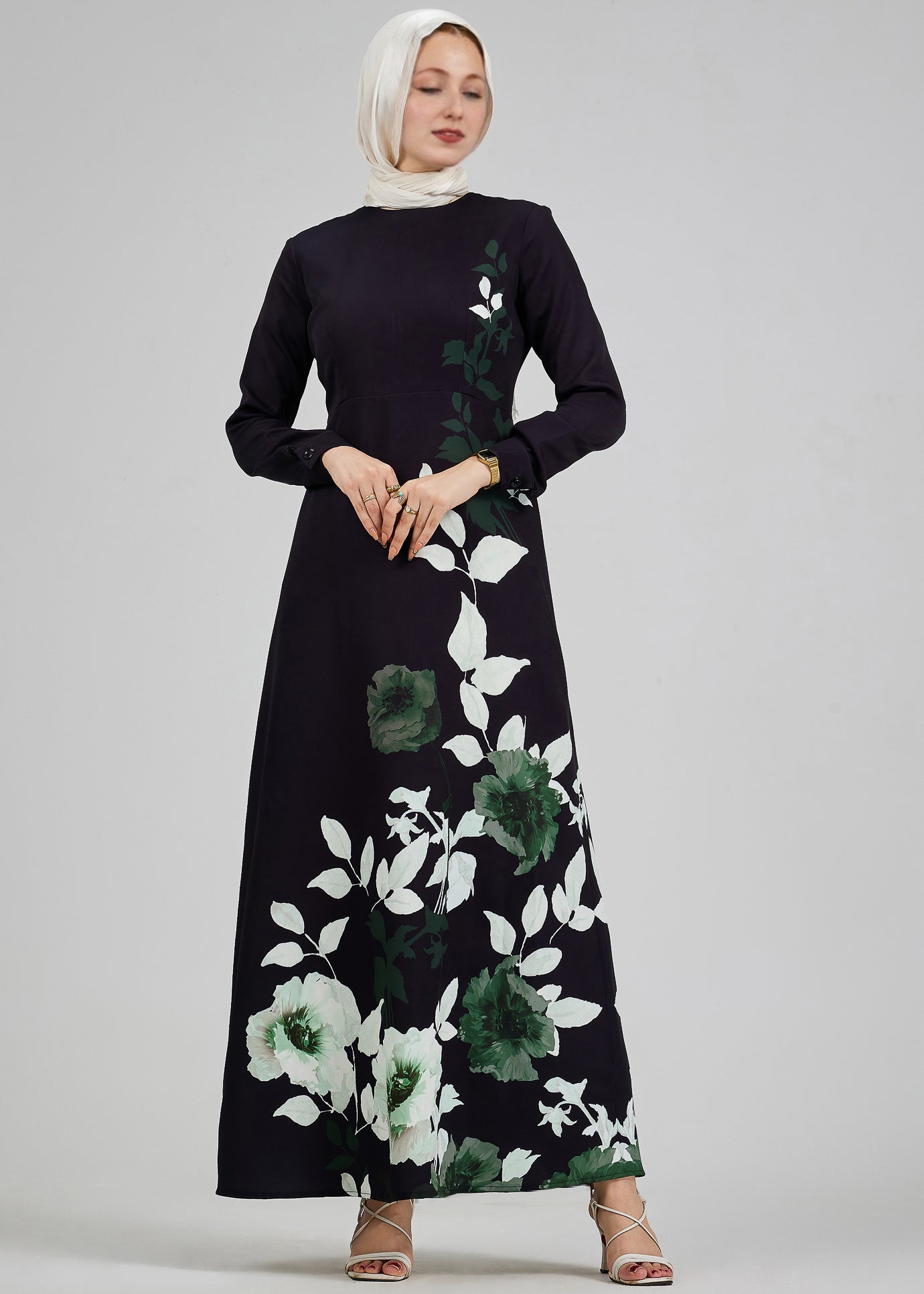 Backside view of a black floral maxi dress with subtle leaf accents, worn by a woman in a hijab.