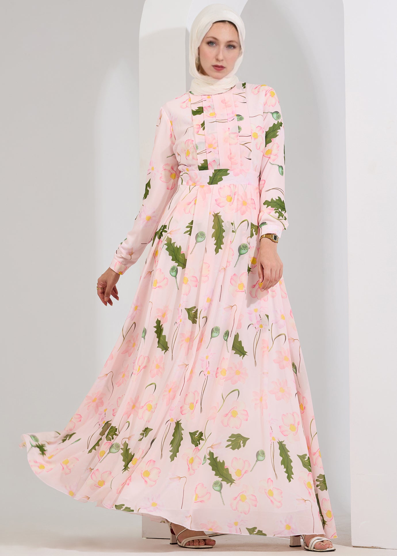 Model seated in blush floral chiffon maxi dress smiling