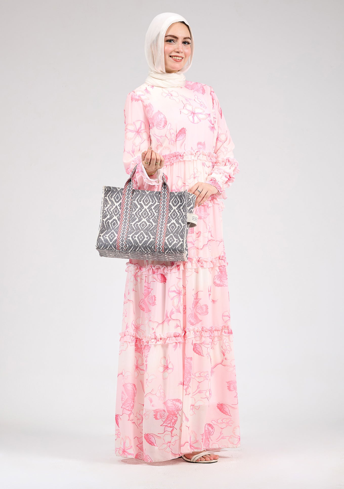 Model standing in a delicate floral chiffon maxi dress with ruffle tiers