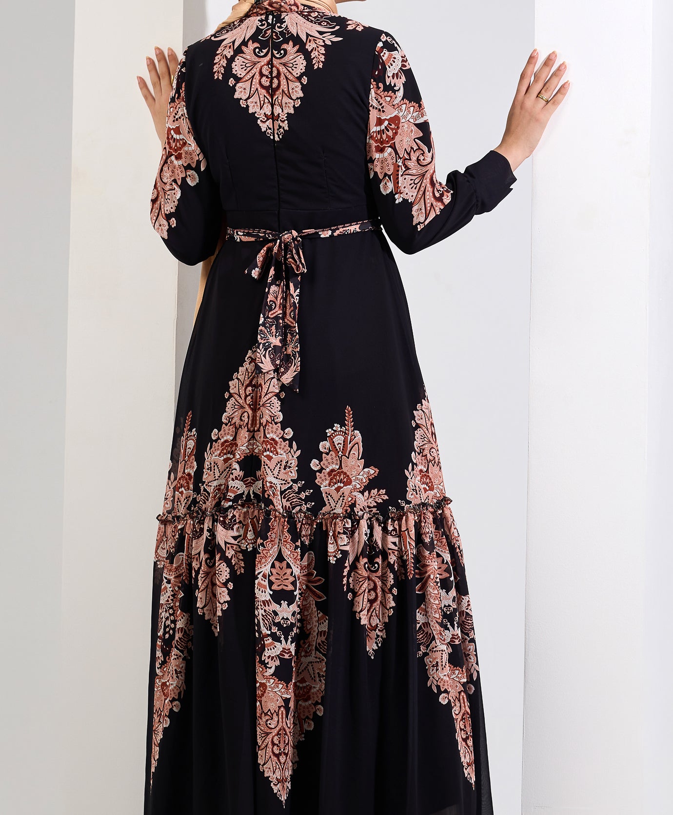 Back view of a black chiffon maxi dress with peach floral print, showing the tied waist detail