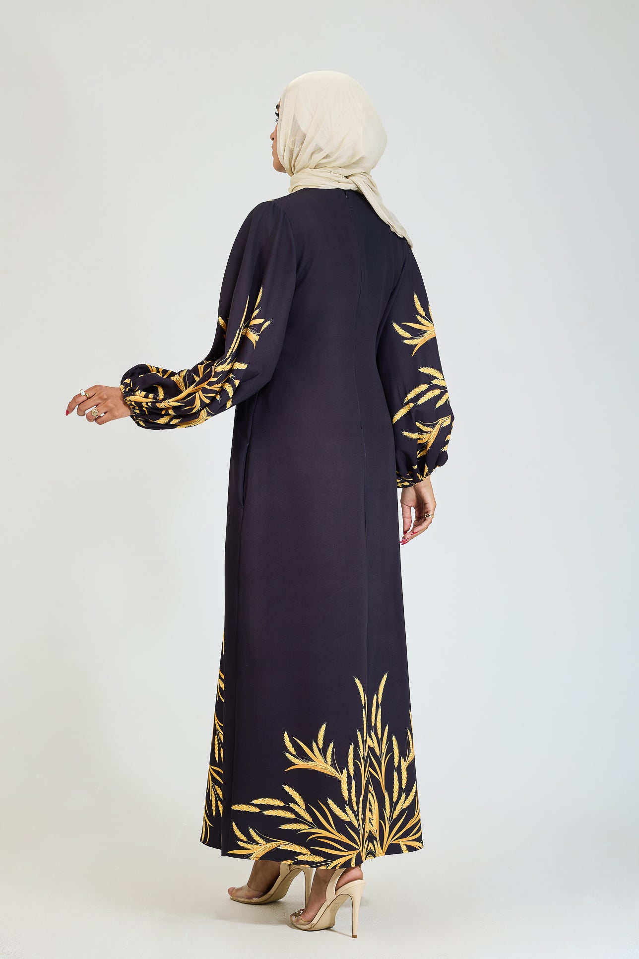 Back view of black crepe modesty dress with golden leaf pattern.
