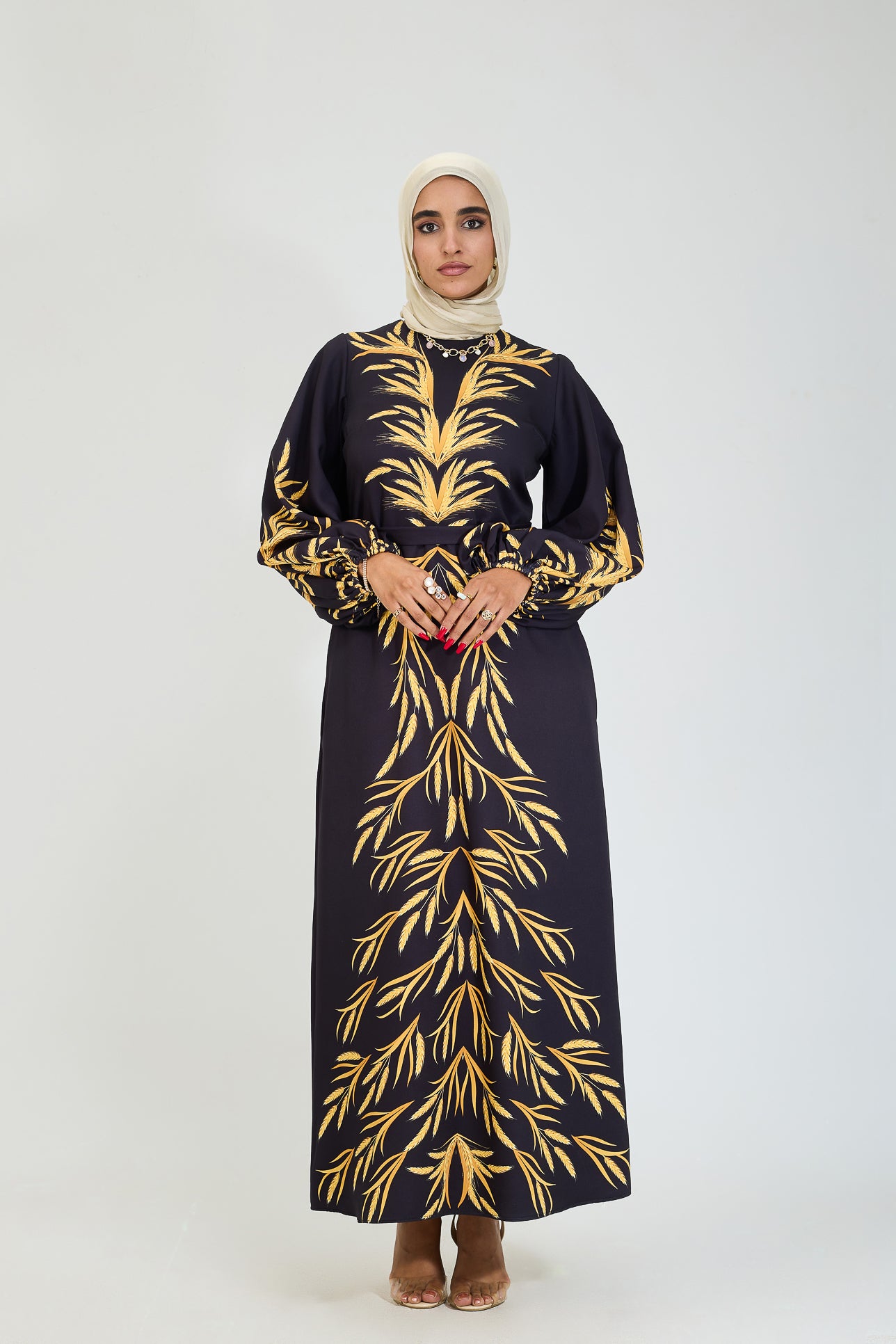 Close-up of flared sleeve with golden leaf design on black modesty dress.
