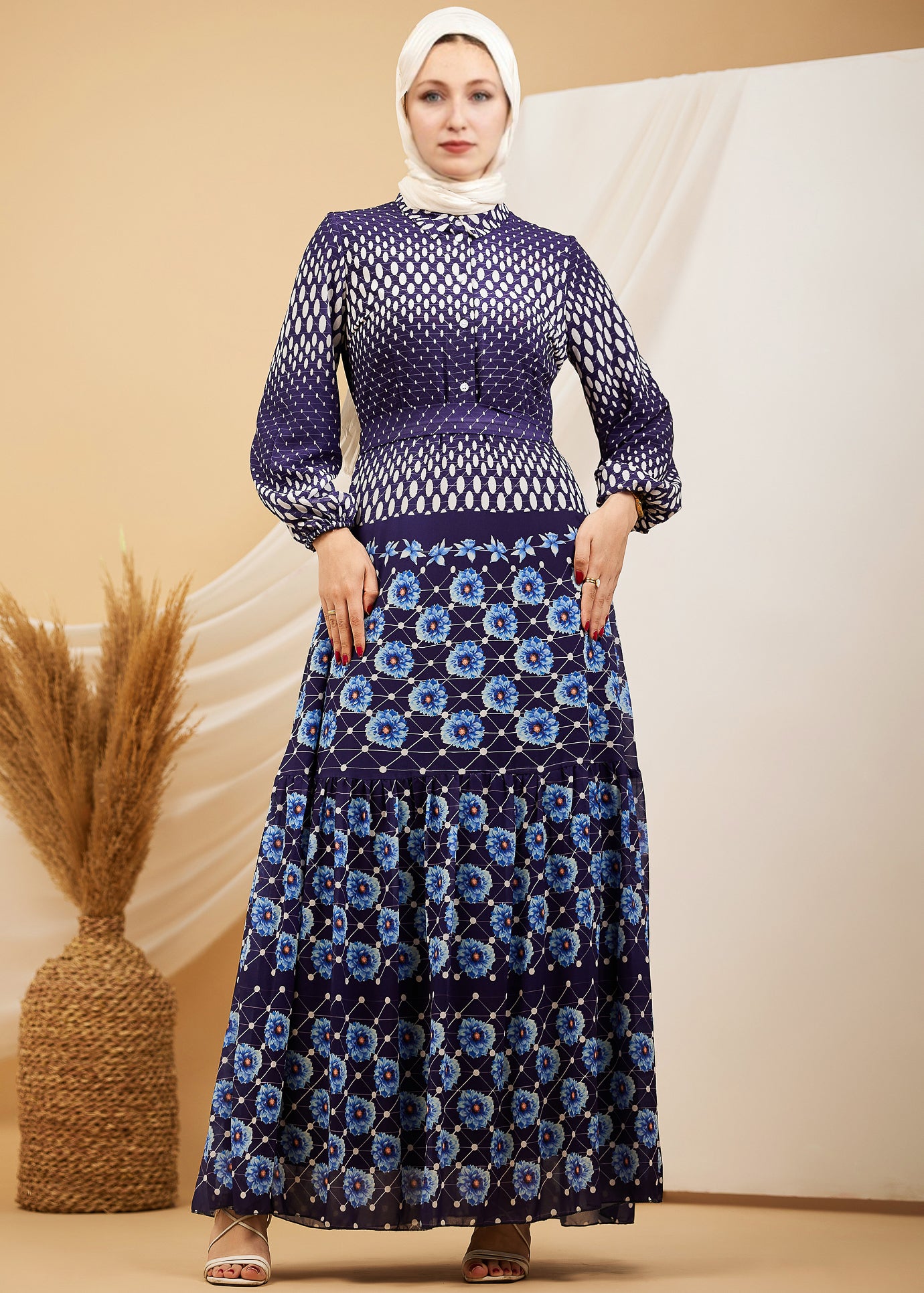 Model posing in a navy floral chiffon maxi dress with intricate patterns and button-down front