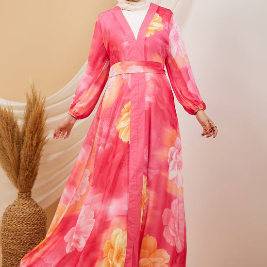 Front view of a model in a coral floral chiffon maxi dress with flared sleeves