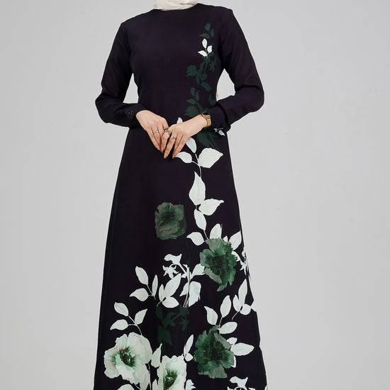 Full front view of a woman wearing an elegant black floral maxi dress, with green and white leaf accents