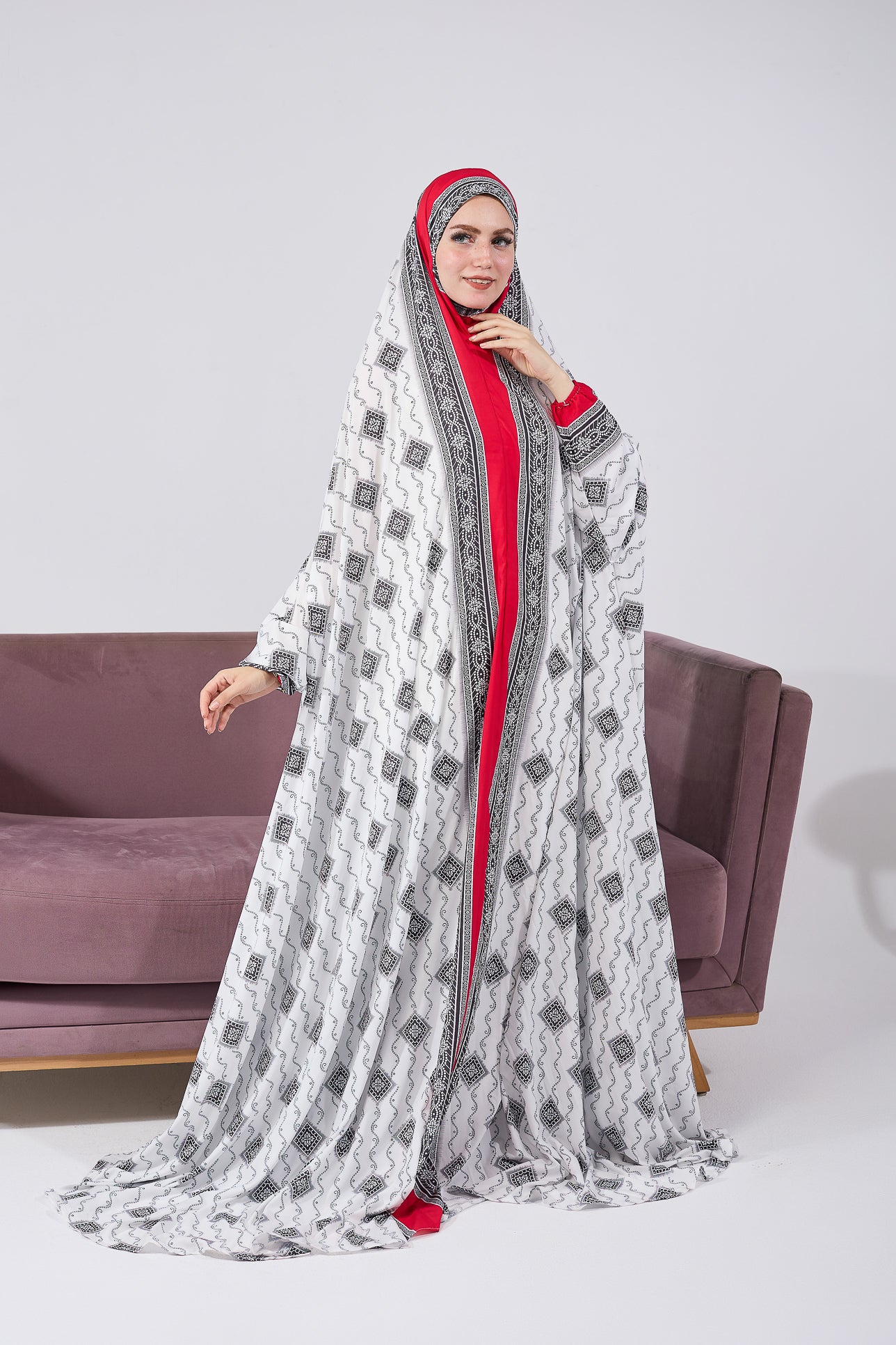 Model standing in black and white patterned satin prayer gown with red inner layer