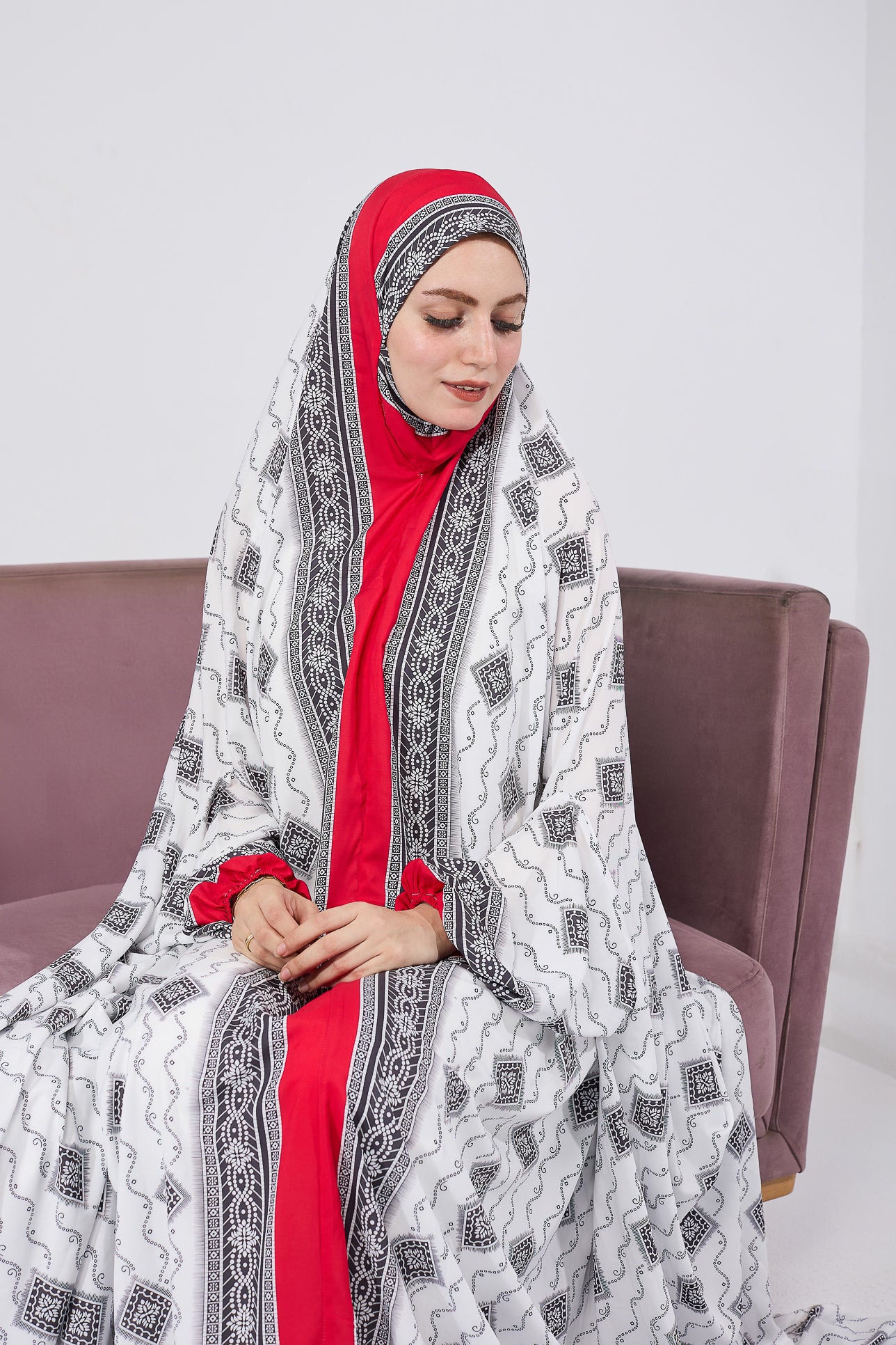 Woman smiling in satin prayer gown with black and white print and vibrant red underlayer